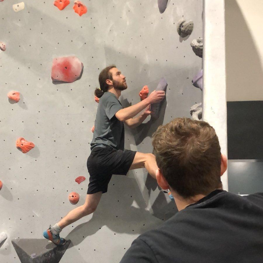 Me stretching across holds while solving a problem on a bouldering wall